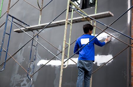 Young builder hand grinding wall with sandpaper on building siteの写真素材