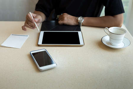 Interior design man working on tablet with coffee cup and cell phone on the tableの写真素材