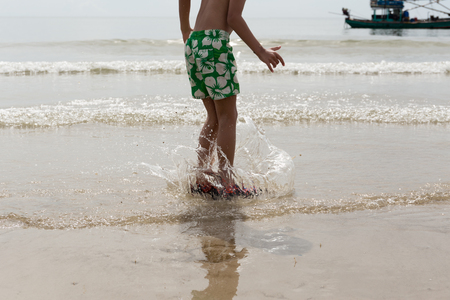 Little boy having fun jumping on the beach at the day time on vacationの写真素材