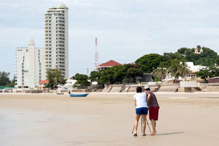 Couple taking picture using tripod on the beach on vacationの写真素材