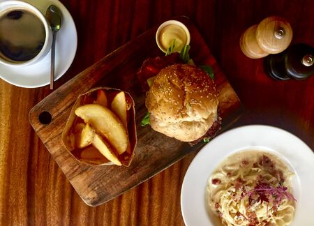 Hamburger and Spaghetti carbonara with chips and coffee on the tableの写真素材