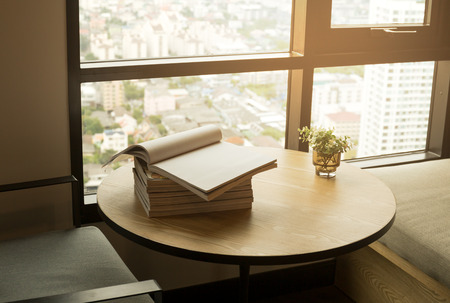 Wooden table with an opened book and plant on window with sunlightの写真素材