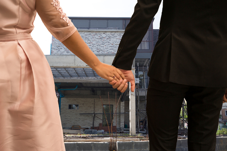 Wedding couple hand holding hands standing on front of house construction conceptualの写真素材
