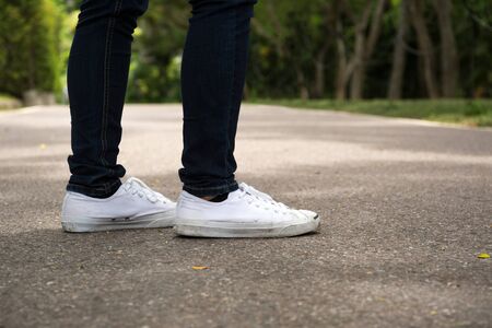 Fashion hipster woman with white sneakers standing on concrete roadの写真素材