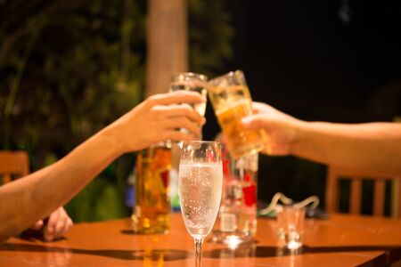 Glass of champagne with people holding glasses making a toast for celebration at nightの写真素材