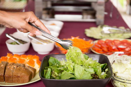 Selected focus woman taking fresh vegetable salad from salad bowl for breakfastの写真素材