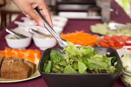Selected focus woman taking fresh vegetable salad from salad bowl for breakfastの写真素材