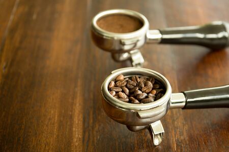 Coffee filter holders for coffee machine with beans and coffee ground on wooden tableの写真素材