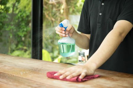 Waiter cleaning the table with spray disinfectant in a restaurant