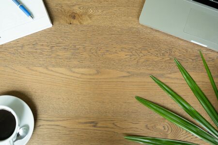 Top view office accessories with laptop paper coffee and plant leaf on wooden desk background.の写真素材