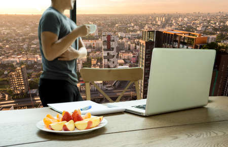 Business vision man hand holding coffee cup with beautiful sunrise over city conceptualの写真素材
