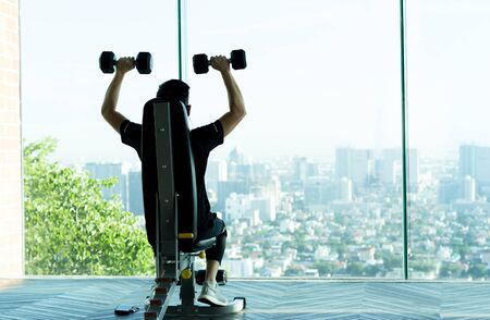 Man work out with dumbbells at the gym with city viewの写真素材