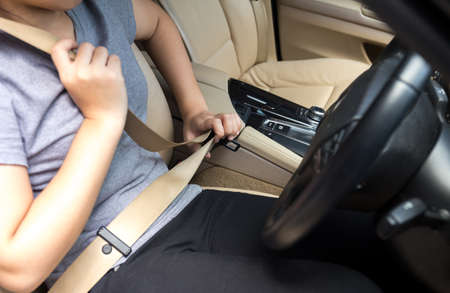 Young woman hand fastening a seat belt before drivingの写真素材
