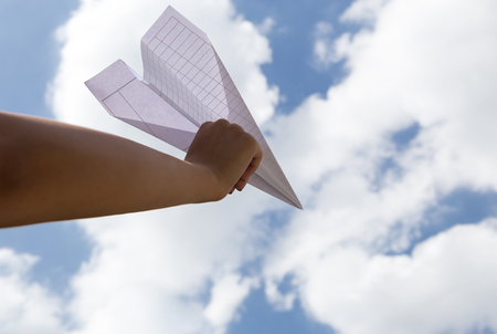 Imagination of woman hand throwing paper plane into skyの写真素材