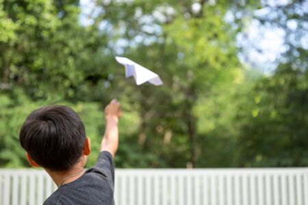 Little boy playing with a paper plane in summerの写真素材