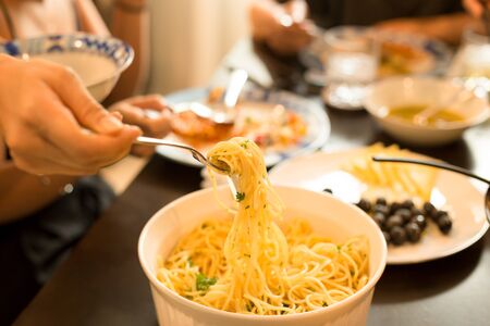 Family dinner spaghetti with olive oil and parsley on a forkの写真素材