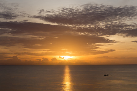 Top view sunrise over ocean with fishing boat with golden sky cloudの写真素材