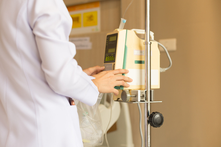 Nurse's hand operating IV machine in patient room in hospitalの写真素材