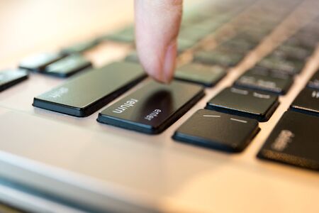 Conceptual people finger put the enter button on laptop keyboard in macro