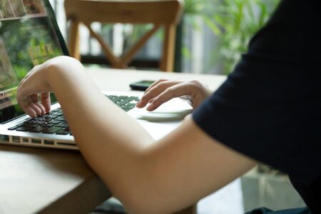 Selected focus woman hand working on computer keyboard in cafeの写真素材