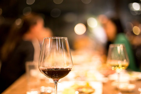 Shot in high iso with low light glass of red on the table defocussed light backgroundの写真素材