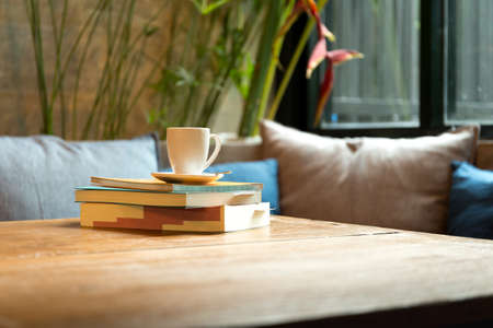 Stack of book with coffee cup on top on wooden tableの写真素材