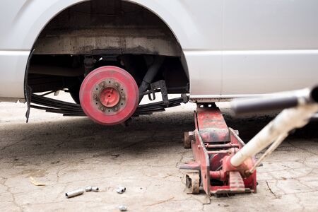 Car lifted with red hydraulic floor Jack for trie replacement in garageの写真素材