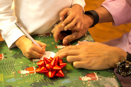 Shot in low light with high ISO young boy writing a Christmas card with his fatherの写真素材