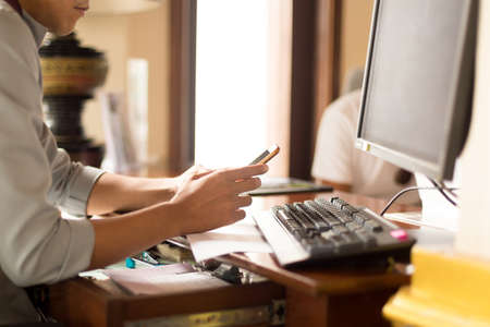 Man hand use phone and pc computer internet at office deskの写真素材