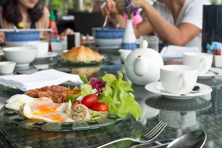 Breskfat set with fried eggs and vegetable salad with tea pot and coffee ready for eat with friendの写真素材