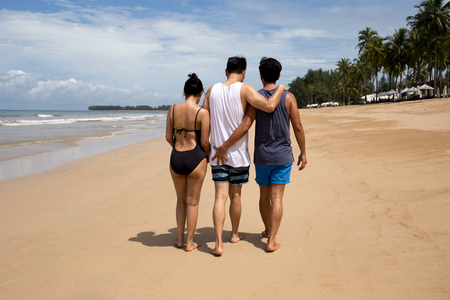 Threesome love friends of two men and one woman on the beach. Concept Love gayの写真素材