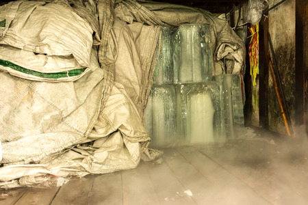 Large cubes of clear ice cover with plastic sack in ice factoryの写真素材