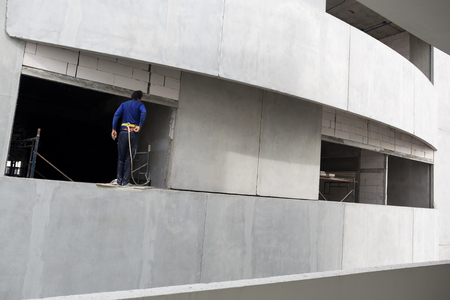 Builder with rope at high building in construction siteの写真素材