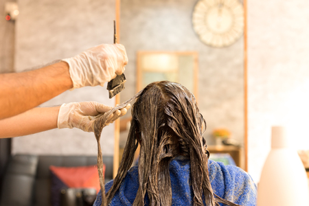 Professional hairdresser dyeing hair for customer in salonの写真素材