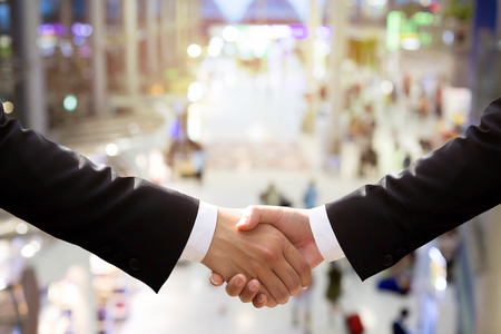 Business hand shake with motion blur people in backgroundの写真素材