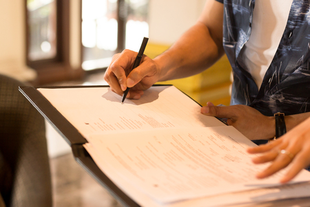Mans hand signing agreement from for hotel reservationの写真素材