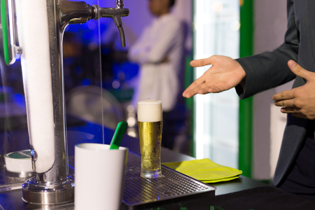 Waiter with glass of  beer in pub at nightの写真素材