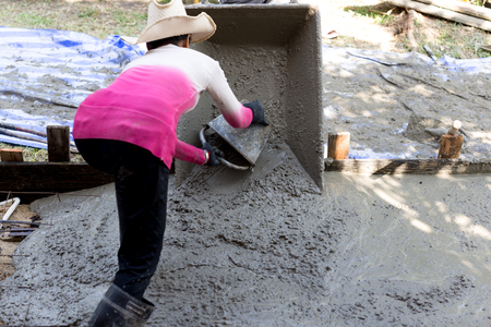 Woman construction worker poured concrete floors with bucketの写真素材