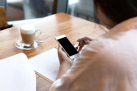 businesswoman using cell phone with cup of coffee while working in finances bankingの写真素材
