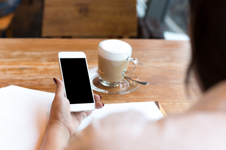 businesswoman using cell phone with cup of coffee while working in finances bankingの写真素材