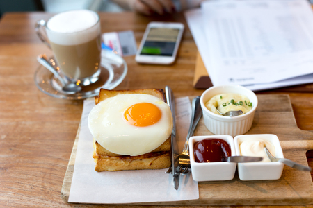 Toast cheese sandwiches with fried egg and coffee with businesswoman working in backgroundの写真素材