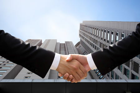 Successful business hand shaking hand agreement on building in backgroundの写真素材