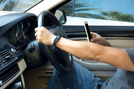 Man using phone while driving the car dangerous transportation conceptの写真素材