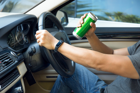 Dangerous driving concept man drinking beer while driving a carの写真素材