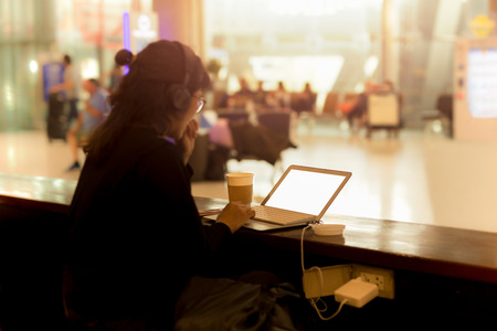 Tourist woman working on laptop with headphone in a coffee shop at the airportの写真素材