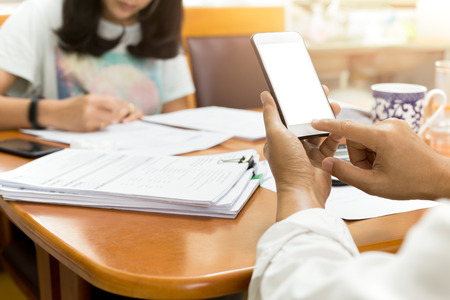 Businessman using cell phone working with partner in finance tax accounting at homeの写真素材