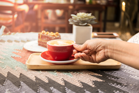 Female hand with cup of coffee and chocolate cake on the table Top viewの写真素材