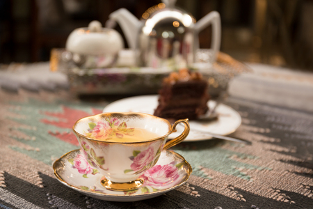 Cup of tea and slice of chocolate and tea pot in backgroundの写真素材