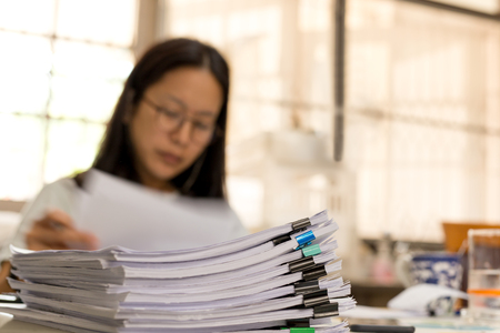 Business woman working at home with huge pile of document folders on the tableの写真素材