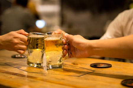 Shot in low light friends toasting with glasses beer at the pubの写真素材